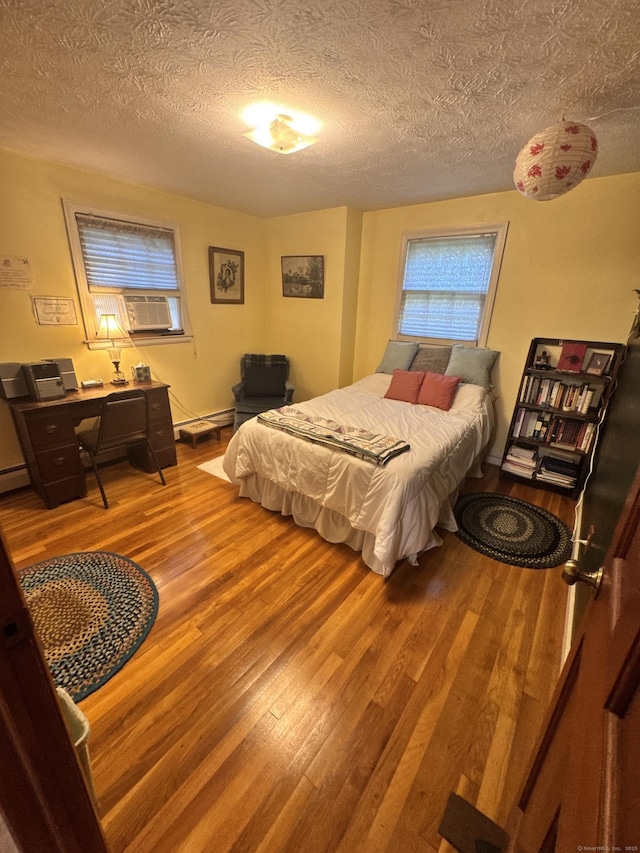 8 Juniper Rd, Windsor, CT 06095 - bedroom with wood finished floors, a textured ceiling, cooling unit, a baseboard radiator, and a desk