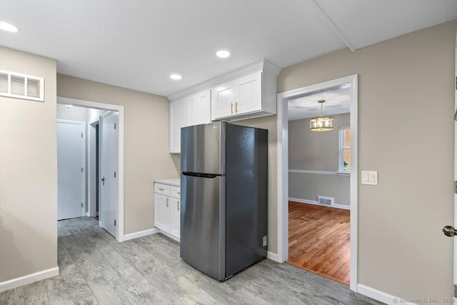 210 Highland Ave, West Haven, CT 06516 - kitchen with freestanding refrigerator, light wood-style flooring, white cabinets, light countertops, and a chandelier