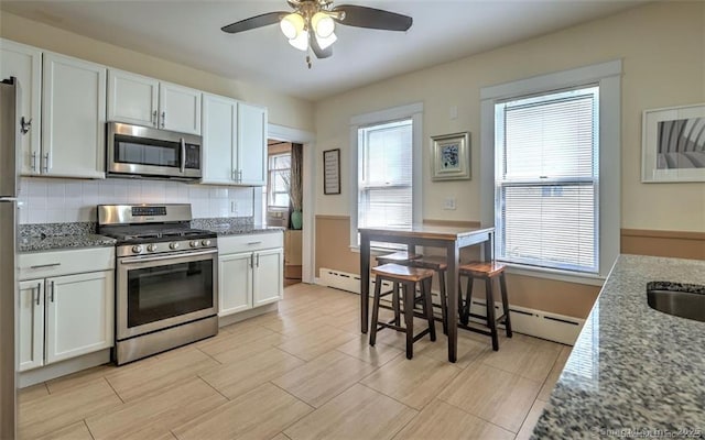 125 Marion St, Bridgeport, CT 06606 - kitchen featuring stainless steel appliances, a ceiling fan, decorative backsplash, and white cabinets