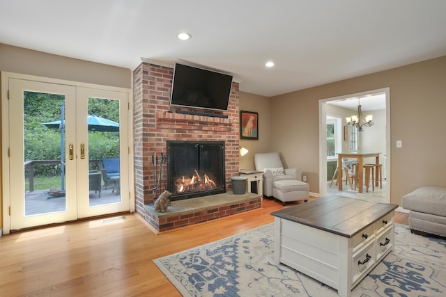 731 N Park Ave, Redding, CT 06896 - living area featuring light wood-style floors, french doors, a brick fireplace, a chandelier, and recessed lighting