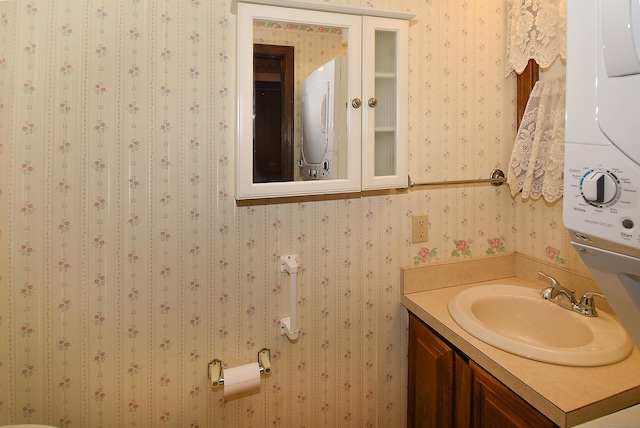 415 Lady Bug Ln Unit 415, Vernon, CT 06066 - bathroom with stacked washing machine and dryer, vanity, and wallpapered walls
