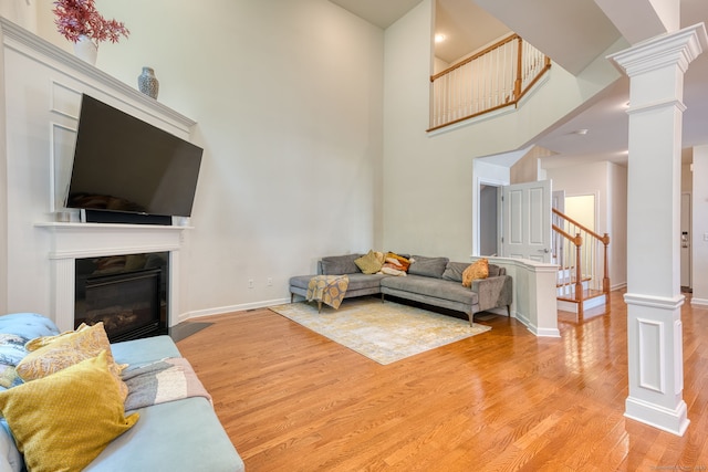 188 Sterling Dr Unit 188, Newington, CT 06111 - living area featuring decorative columns, light wood-style floors, stairway, a towering ceiling, and a fireplace with flush hearth