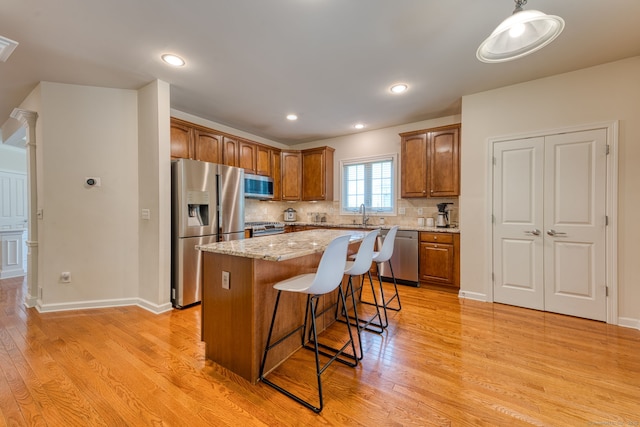 188 Sterling Dr Unit 188, Newington, CT 06111 - kitchen with stainless steel appliances, a kitchen bar, light wood finished floors, light stone counters, and a center island