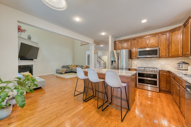 188 Sterling Dr Unit 188, Newington, CT 06111 - kitchen featuring appliances with stainless steel finishes, open floor plan, a breakfast bar area, light stone countertops, and decorative backsplash