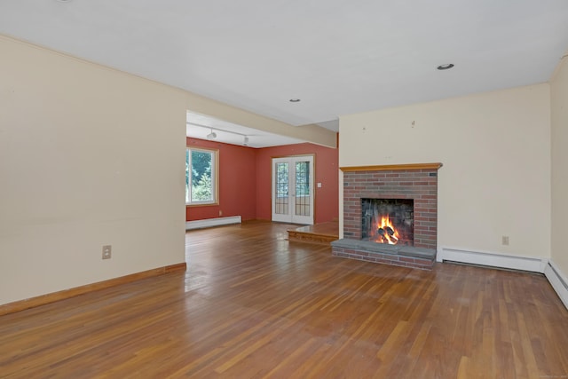 27 Tuttle Ct, Bethany, CT 06524 - unfurnished living room with baseboard heating, wood finished floors, a brick fireplace, and a baseboard heating unit