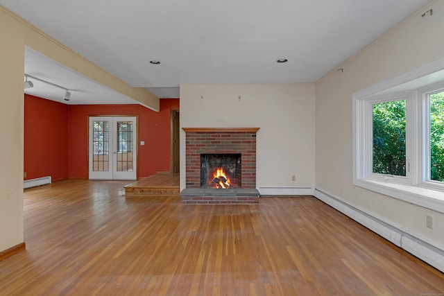 27 Tuttle Ct, Bethany, CT 06524 - unfurnished living room with a baseboard radiator, a baseboard heating unit, wood finished floors, a brick fireplace, and rail lighting