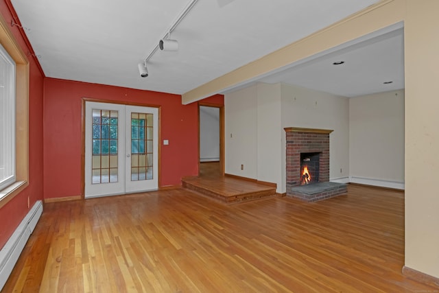 27 Tuttle Ct, Bethany, CT 06524 - unfurnished living room featuring light wood-type flooring, a baseboard heating unit, french doors, a fireplace, and a baseboard radiator