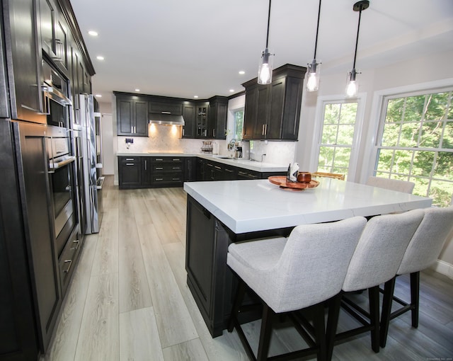 625 Lakeview Rd, Orange, CT 06477 - kitchen featuring stainless steel appliances, tasteful backsplash, a center island, recessed lighting, and light wood-type flooring