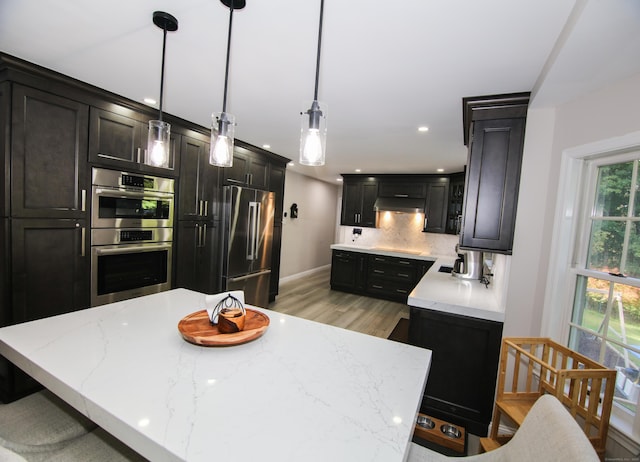 625 Lakeview Rd, Orange, CT 06477 - kitchen featuring appliances with stainless steel finishes, decorative backsplash, under cabinet range hood, light wood-style floors, and light stone counters