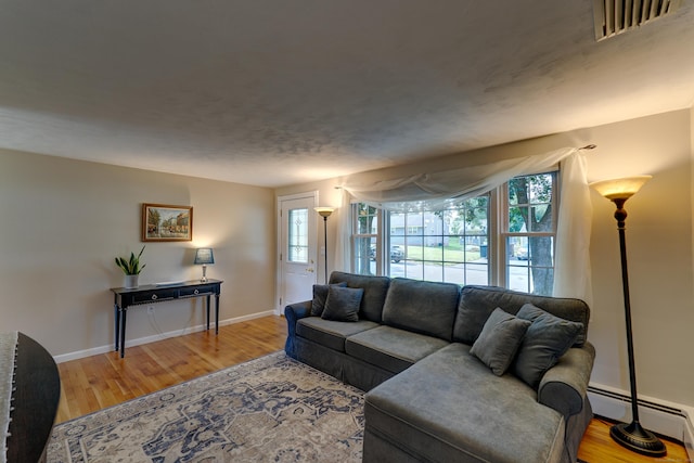 23 Sun St, Enfield, CT 06082 - living area featuring baseboard heating, healthy amount of natural light, and wood finished floors