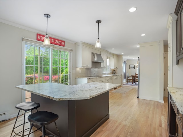 22 Rocky Ridge Dr, Trumbull, CT 06611 - kitchen with wall chimney range hood, a breakfast bar area, light stone countertops, backsplash, and light wood-style floors