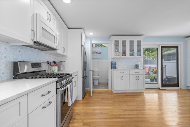 35 Lawrence Ave, Milford, CT 06460 - kitchen with appliances with stainless steel finishes, white cabinets, light countertops, tasteful backsplash, and light wood-style flooring