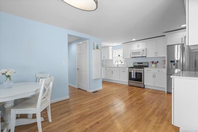 35 Lawrence Ave, Milford, CT 06460 - kitchen featuring stainless steel appliances, backsplash, light countertops, white cabinetry, and light wood-style floors
