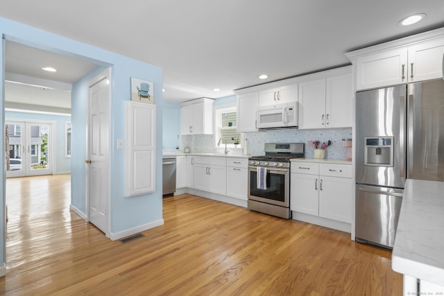 35 Lawrence Ave, Milford, CT 06460 - kitchen with appliances with stainless steel finishes, light wood finished floors, tasteful backsplash, white cabinetry, and recessed lighting