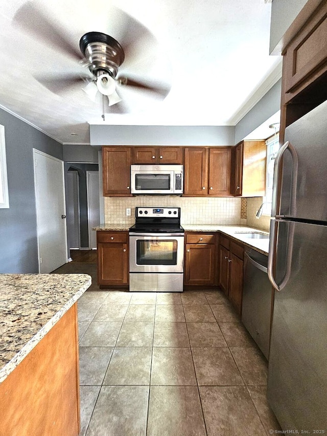 108 French St, Bristol, CT 06010 - kitchen featuring stainless steel appliances, backsplash, a ceiling fan, tile patterned flooring, and brown cabinets