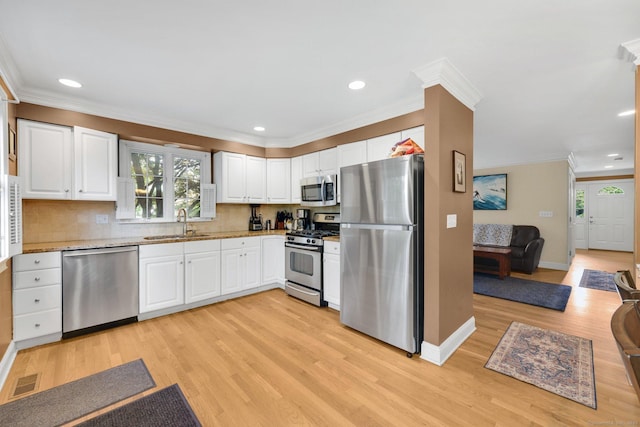 668 Kings Hwy W Unit 668, Fairfield, CT 06890 - kitchen featuring appliances with stainless steel finishes, ornamental molding, light wood-style flooring, white cabinetry, and decorative backsplash