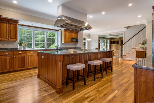 4 Brighton Ln, Simsbury, CT 06070 - kitchen featuring black microwave, a kitchen island, light wood-style floors, crown molding, and brown cabinets