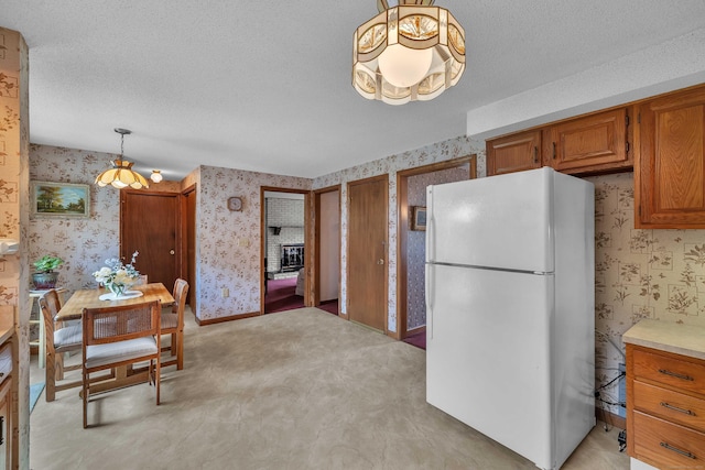 21 Briarcliffe Trl, Old Saybrook, CT 06475 - kitchen featuring freestanding refrigerator, wallpapered walls, brown cabinetry, light countertops, and hanging light fixtures