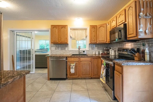 82 Pleasant St, Thomaston, CT 06787 - kitchen featuring appliances with stainless steel finishes, tasteful backsplash, a textured ceiling, dark stone counters, and brown cabinetry