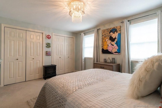 40 Orchard Brook Dr Unit 40, Wethersfield, CT 06109 - carpeted bedroom with multiple closets, a wood stove, and a chandelier