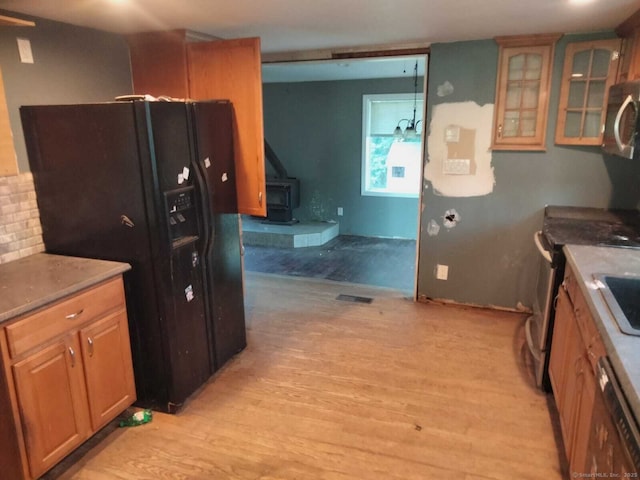 142 S Center St, Windsor Locks, CT 06096 - kitchen with a wood stove, black fridge, light wood-style floors, stainless steel microwave, and dishwashing machine