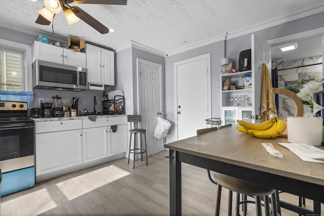 237 Helen St, Bridgeport, CT 06608 - kitchen with appliances with stainless steel finishes, light wood-style flooring, white cabinetry, ornamental molding, and a ceiling fan