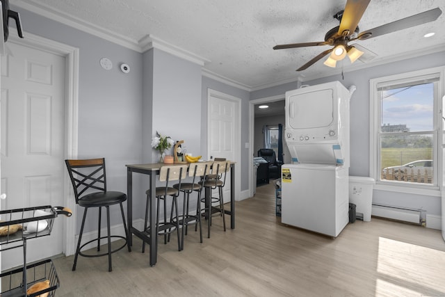 237 Helen St, Bridgeport, CT 06608 - dining area with stacked washer / drying machine, a ceiling fan, a baseboard radiator, a textured ceiling, and light wood-style flooring