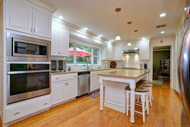 11 Sweetbriar Ln, Newtown, CT 06482 - kitchen featuring appliances with stainless steel finishes, white cabinetry, under cabinet range hood, a kitchen island, and light stone countertops