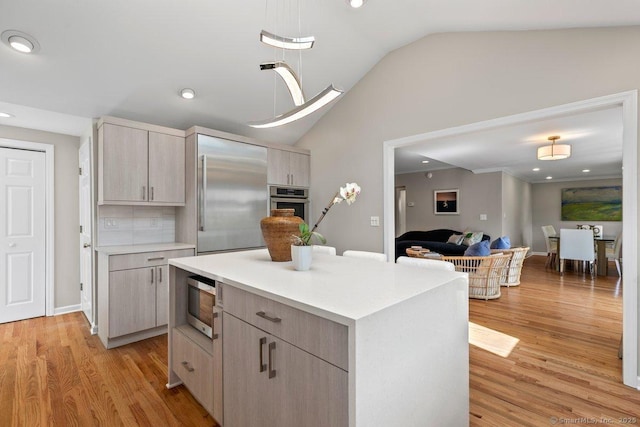 6 Tonetta Cir, Norwalk, CT 06855 - kitchen featuring built in appliances, vaulted ceiling, light wood-style flooring, light countertops, and a center island
