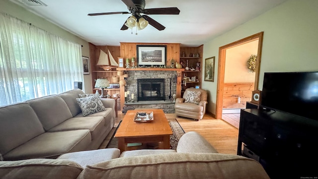 70 River Rd, Preston, CT 06365 - living area with light wood-style floors, a ceiling fan, wooden walls, and a glass covered fireplace
