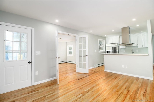18 Greenbrier Rd, East Hartford, CT 06118 - kitchen with range hood, a baseboard heating unit, white cabinets, french doors, and plenty of natural light