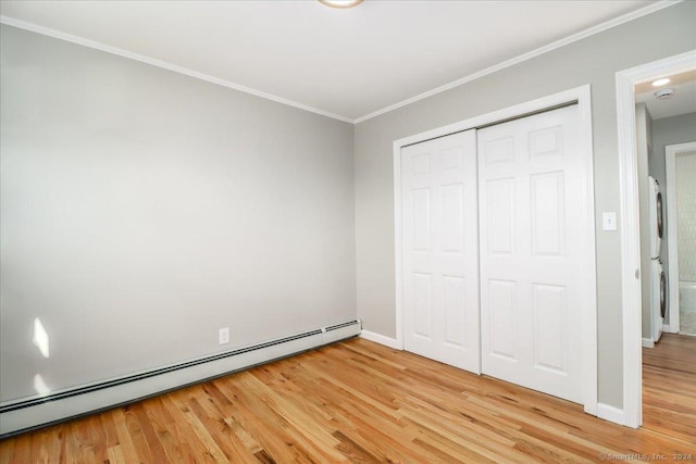 18 Greenbrier Rd, East Hartford, CT 06118 - unfurnished bedroom featuring a baseboard heating unit, stacked washing machine and dryer, light wood-type flooring, crown molding, and a closet