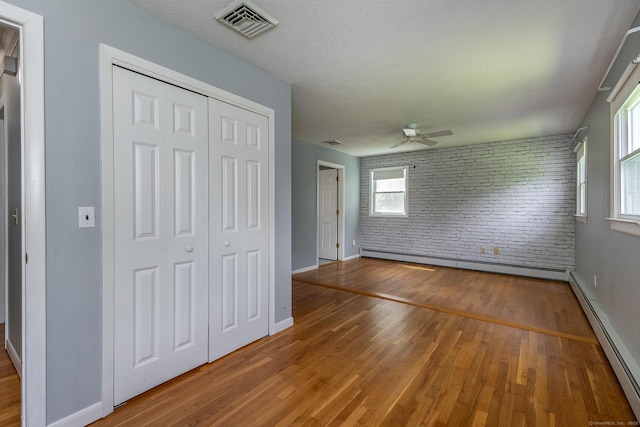 21 Brentwood Rd, New Milford, CT 06776 - unfurnished bedroom with baseboard heating, wood finished floors, brick wall, a closet, and a ceiling fan