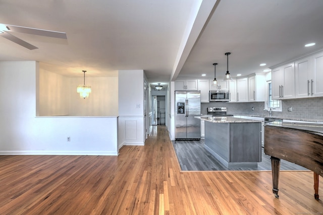 43 Berner Ter, Milford, CT 06460 - kitchen with appliances with stainless steel finishes, wood finished floors, backsplash, white cabinetry, and a kitchen island