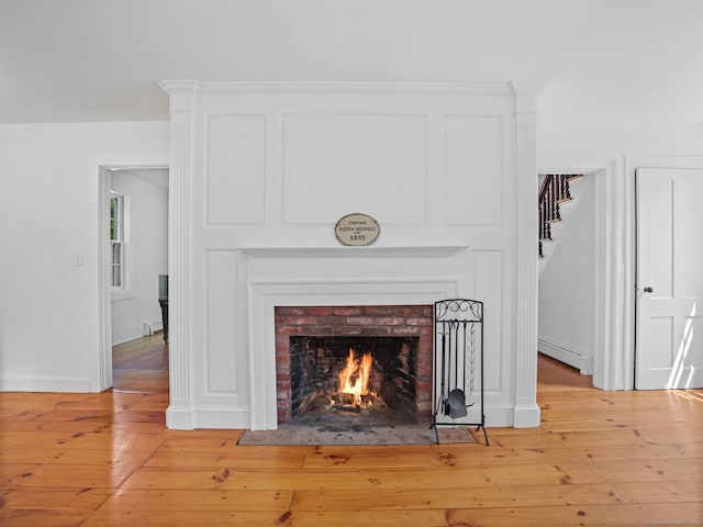 161 White St, Stratford, CT 06615 - detailed view of a baseboard heating unit, wood finished floors, and a fireplace
