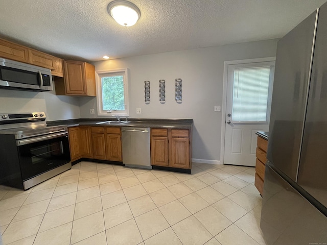 56 Elm St Apt 36, Enfield, CT 06082 - kitchen with appliances with stainless steel finishes, dark countertops, brown cabinets, a textured ceiling, and light tile patterned floors