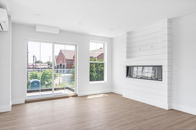 32 Broadway Ave, Stonington, CT 06355 - unfurnished living room with wood finished floors, an AC wall unit, a glass covered fireplace, and a wall mounted AC