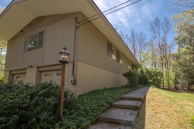 87 Pleasant Dr, Bethany, CT 06524 - view of side of property with an attached garage, a lawn, and stucco siding