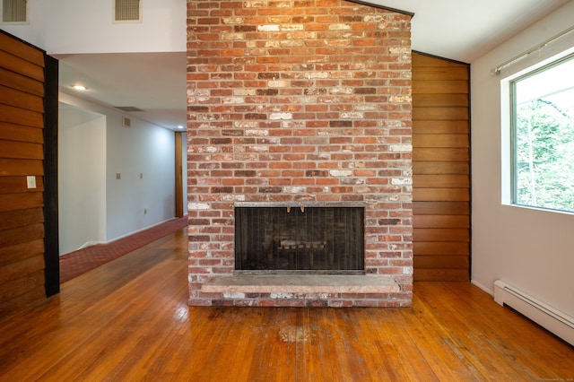 87 Pleasant Dr, Bethany, CT 06524 - unfurnished living room with a baseboard heating unit, wood-type flooring, vaulted ceiling, and a fireplace