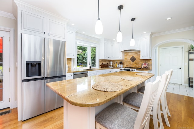 89 Honey Hill Rd, New Hartford, CT 06057 - kitchen with appliances with stainless steel finishes, light wood-type flooring, white cabinetry, decorative backsplash, and ornamental molding