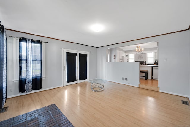 53 Wells Ave, East Hartford, CT 06108 - unfurnished living room featuring a chandelier, wood finished floors, healthy amount of natural light, and crown molding