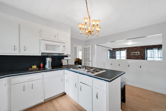 53 Wells Ave, East Hartford, CT 06108 - kitchen featuring white appliances, a peninsula, light wood-style flooring, tasteful backsplash, and ornamental molding