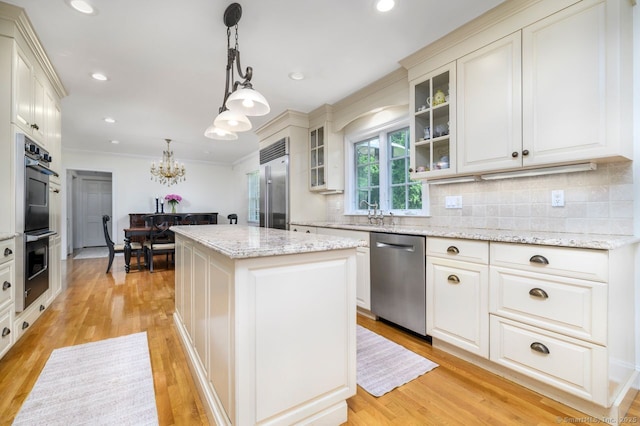 285 Westover Rd, Stamford, CT 06902 - kitchen featuring appliances with stainless steel finishes, a center island, backsplash, light wood-type flooring, and ornamental molding