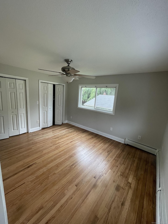 37 W Normandy Dr, West Hartford, CT 06107 - unfurnished bedroom featuring a baseboard radiator, two closets, light wood-style flooring, a ceiling fan, and a textured ceiling
