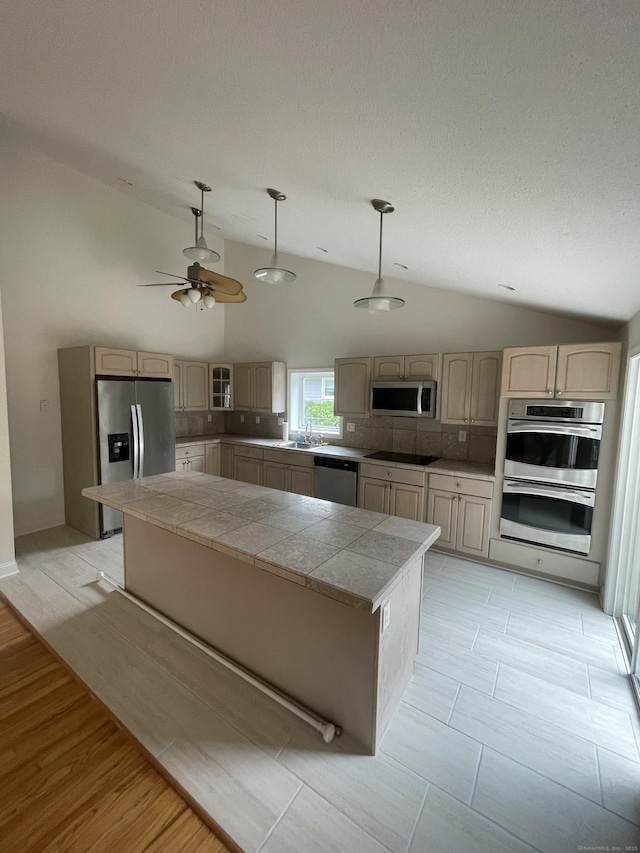 37 W Normandy Dr, West Hartford, CT 06107 - kitchen with appliances with stainless steel finishes, vaulted ceiling, a kitchen island, decorative backsplash, and hanging light fixtures
