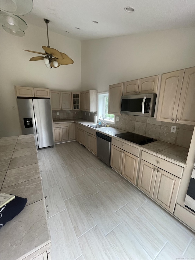 37 W Normandy Dr, West Hartford, CT 06107 - kitchen with stainless steel appliances, light brown cabinetry, high vaulted ceiling, tile counters, and tasteful backsplash