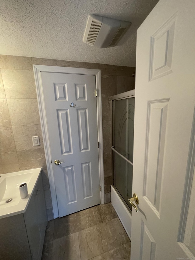 37 W Normandy Dr, West Hartford, CT 06107 - full bathroom featuring tile walls, vanity, a textured ceiling, and enclosed tub / shower combo