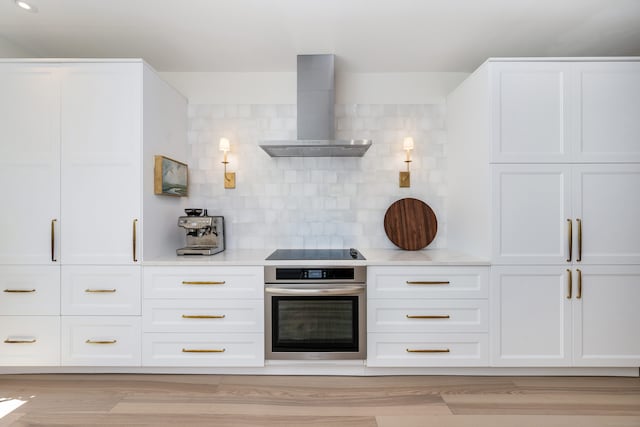 10 Pine Brook Ln Unit 10, Darien, CT 06820 - kitchen with stainless steel oven, wall chimney range hood, black electric cooktop, white cabinetry, and decorative backsplash