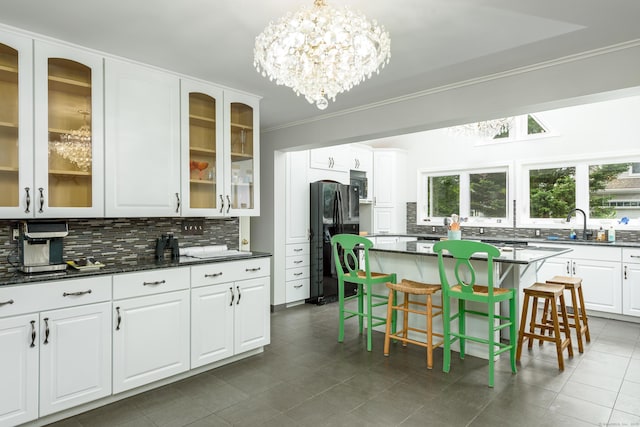 92 Grove Beach Rd S, Westbrook, CT 06498 - kitchen with black refrigerator with ice dispenser, a chandelier, decorative backsplash, crown molding, and a breakfast bar area