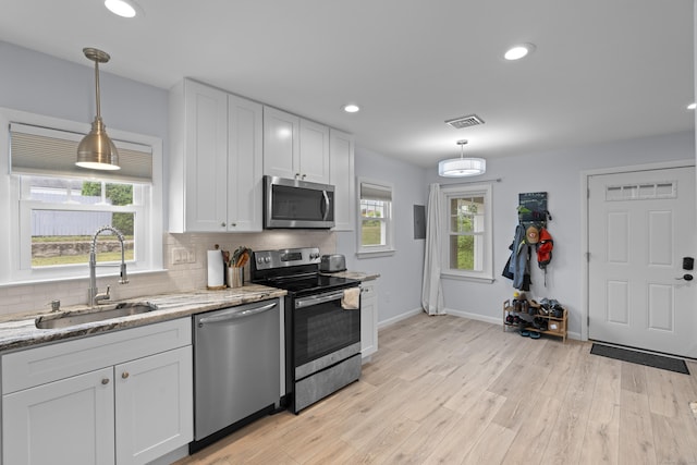 5 Fuller Ct, East Lyme, CT 06357 - kitchen with stainless steel appliances, white cabinets, decorative backsplash, light stone countertops, and light wood finished floors